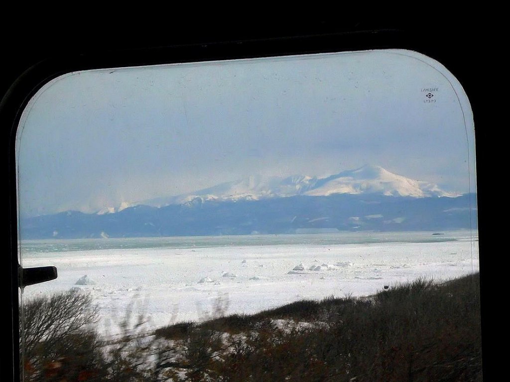 Lokalverkehr in Ost-Hokkaido: Im mittleren Frontfenster des KIHA 54 514 (öffentlich zugänglich) kommt die Rausu-Vulkankette hinter dem Ochotskischen Meer in Sicht. Bei Yamubetsu, 18.Februar 2009. SEMMÔ-LINIE 