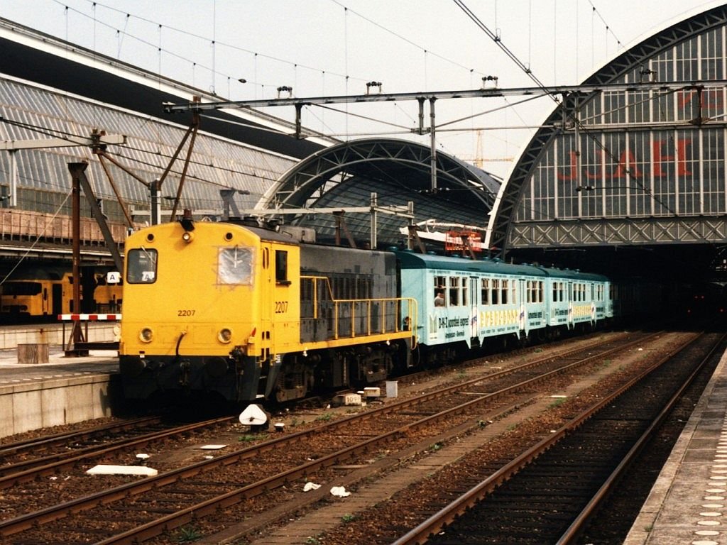 Lovers Rail ist eine Eisenbahnunternehmung der unter den neuen EU-Richtlinien dem Betrieb auf dem NS Netz aufnahm zwischen Amsterdam - Haarlem - IJmuiden. Dazu wrden vom NMBS M2 Wagen gekauft und NMBS E-loks Reihe 25.5 gemietet. Fr den Betrieb auf Haarlem - IJmuiden wrden Dieselloks der NS-Baureihe 2200 gemietet. 2207 und 2202 (hinter) mit Kennemerstrand Expres Amsterdam-IJmuiden auf Bahnhof Amsterdam Hauptbahnhof am 16-8-96. Bild und scan: Date Jan de Vries. 