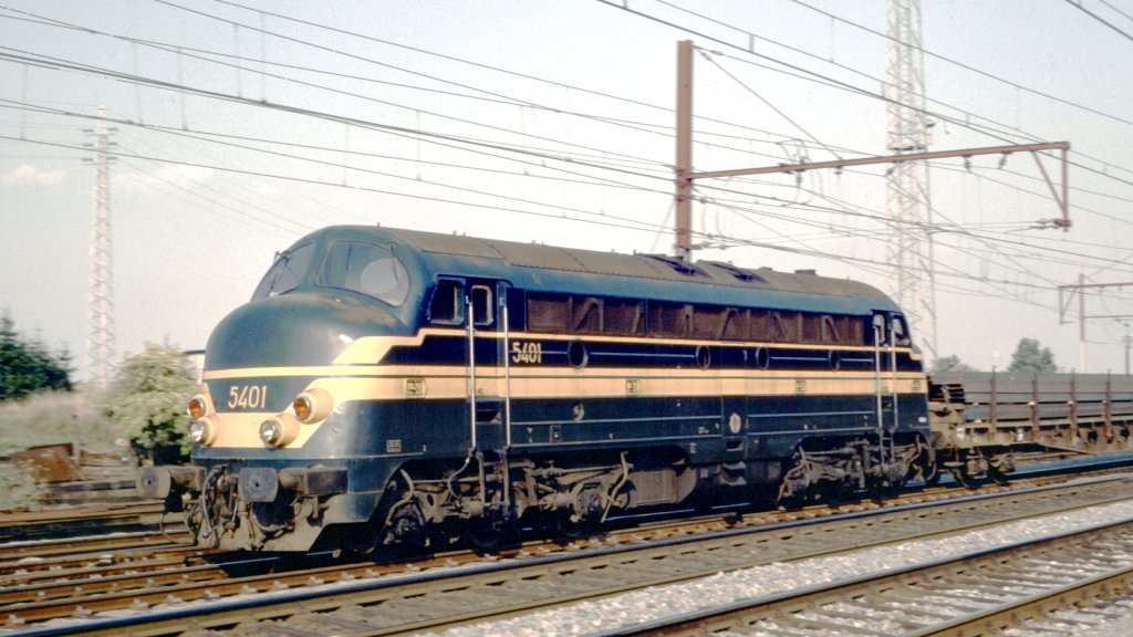 Luxemburg, belgische Diesellok 5401 auf der Strecke Namur - Arlon (Belgien) - Luxemburg. Kleine Serie von 8 Loks die anfangs etwas schneller waren als die Serie 52, entwickelt von General Motors Electro-motive division (EMD), gebaut 1977 von der Anglo-Franco-Belge (AFB), aus dem Verkehr gezogen 2002, CC Diesellok mit 1265 kW und maximal 140 km/h, auf 120 km/h beschrnkt ab 1980.
Scan eines Dias aus dem Jahr 1976.
