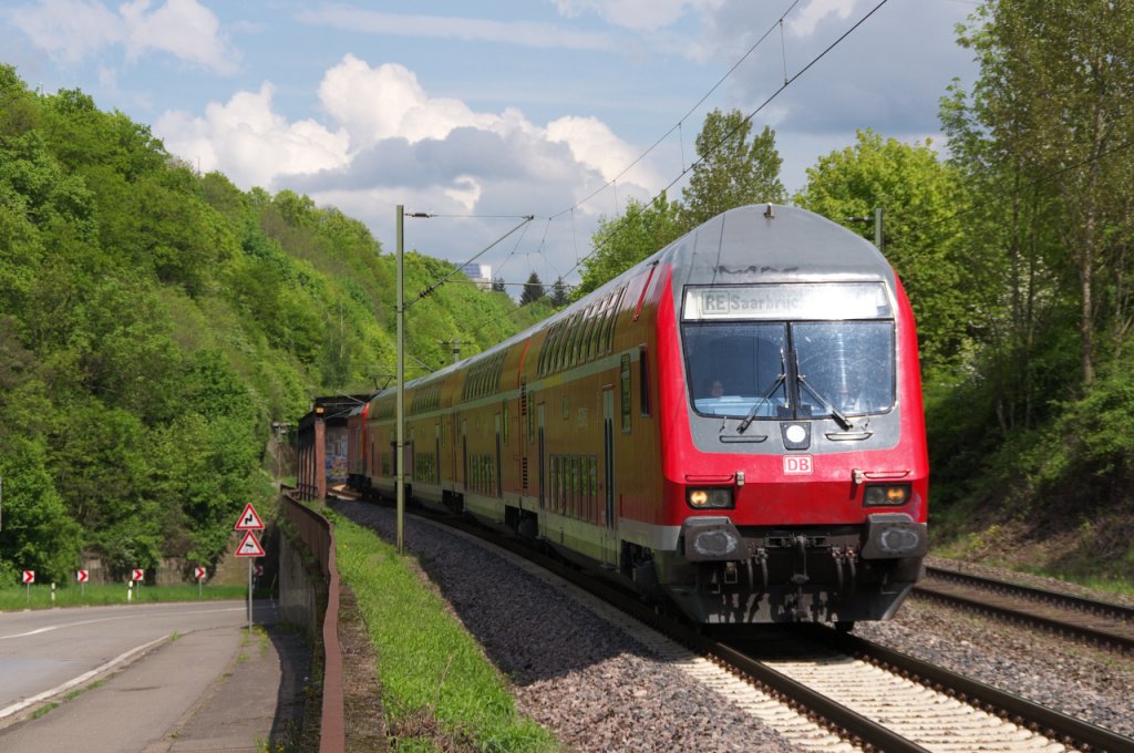 Mal Sonne, mal Wolken so war das Wetter am 7 Mai 2013. Bei angenehmen Temperaturen ist der RE Saarbrcken -Koblenz kurz vor dem Einfahrsignal von Vlklingen.
Es schiebt 143 919. Bis Mitte der 80er Jahre fand der Verkehr an dieser Stelle noch in 3 Etagen statt.
Links unten die Strae (ehemals B51), in der Mitte die Saarstrecke (KBS 685 - Bahnstrecke 3230 Saarbrcken - Karthaus) und die dritte Ebene lsst sich noch erahnen, das war die Bahnstrecke Vlklingen - Lebach. Rechts sieht man noch den Bahndamm der in Hhe des Stromabnehmers ber eine Brcke die KBS 685 berquerte und sofort links im Berg, im Heidstocktunnel verschwand.