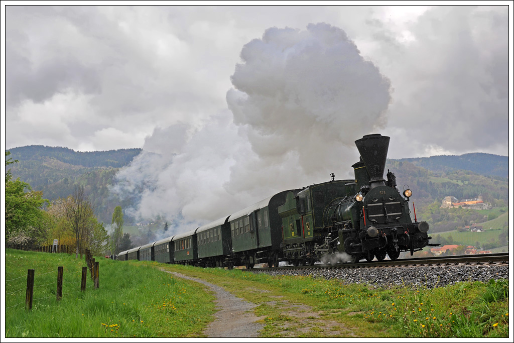 Mit acht Spanten und 400 Fahrgästen nimmt 671 am 21.4.2012 mit ihrem Spz 8521 von Lieboch nach Wies-Eibiswald die Leibenfelder Höhe in Angriff. Im Hintergrund ist die Burg Deutschlandsberg zu sehen. Ich hätte mir an dieser Stelle mehr Regen gewünscht. (21.4.2012)