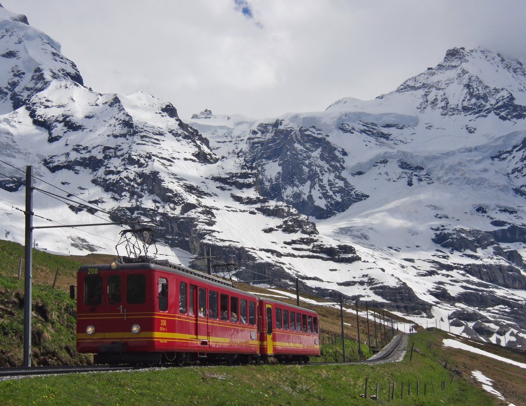 Mit Blick auf das 3454 m hohe Jungfraujoch in der Bildmitte fhrt der 1964 in Betrieb genommene Triebwagen 208 der Jungfraubahn seinem Ziel und Fahrtende, der Kleinen Scheidegg entgegen. Von der 9 km langen Strecke vom Jungfraujoch zur Kleinen Scheidegg befindet sich der Triebwagen am 15.06.2013 auf dem insgesamt nur 2 km kurzen tunnellosen Abschnitt. Nach der Ankunft auf der 2061 m hoch liegenden Kleinen Scheidegg hat der Triebwagen in 50 Minuten Fahrzeit 1400 m Hhenunterschied hinter sich gebracht.