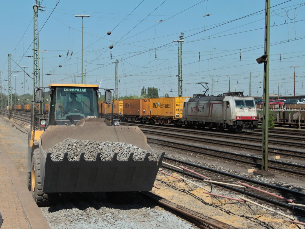 Mit einem Caterpillar 966H Radlader wird am 25.04.2011 neuer Schotter in das Gleisbett von Gleis 2 in Aachen West gefahren. Im Hintergrund wartet Crossrail 185 580-8 (Jana) mit einem Containerzug auf Abfahrt Richtung Kln.
