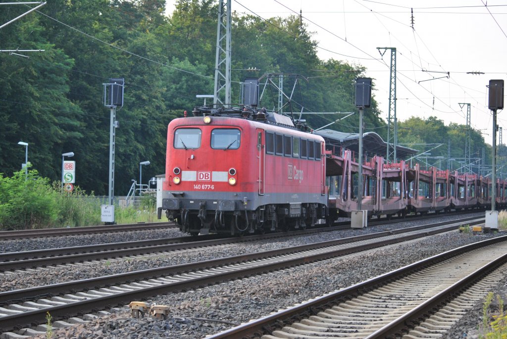 Mit leeren Autowagen durchfhrt 140 677-6 am Abend des 26.07.2012 den Bahnhof von Dreieich-Buchschlag.