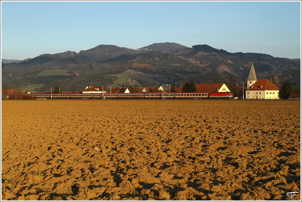 Mit den letzten Sonnenstrahlen fhrt eine Lok der BR 1044 mit IC 537  Alpen Adria Universitt  durch das Aichfeld. 
Lind 2.4.2011