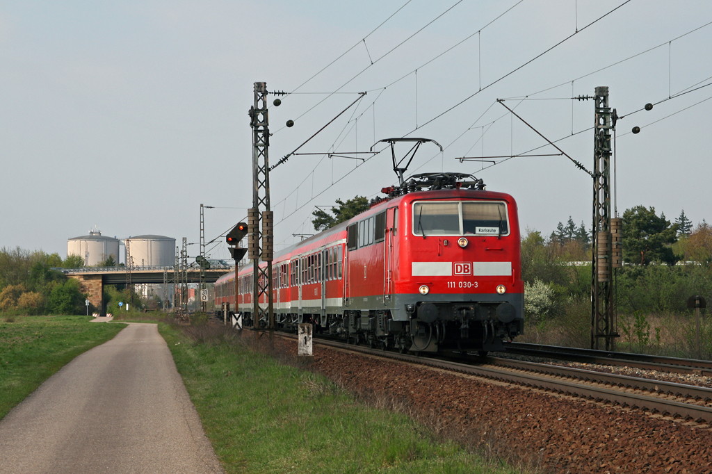 Mit wenigen Minuten Versptung verlsst die Ludwigshafener 111 030 am 16. April 2010 mit der RB 18691 von Mannheim nach Karlsruhe den Bahnhof von Waghusel in Richtung Graben-Neudorf.
