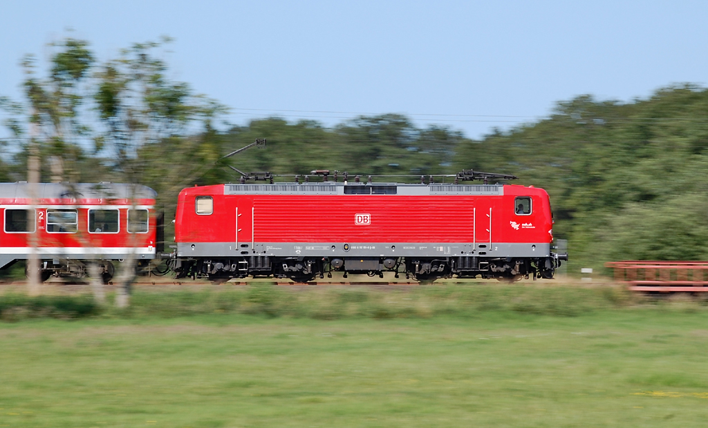 Mitzieher sind eine interessante Sache: Lokomotiven, die nicht sonderlich windschnittig aussehen, wirken durch sie sehr dynamisch. - 112 151 war am 9. Juli 2013 nördlich von Bokelholm auf der KBS 131 in Richtung Süden unterwegs.