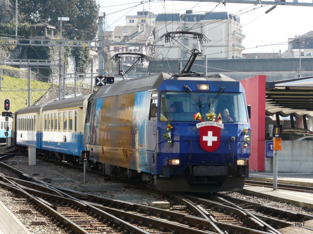 MOB - Einfahrender Goldenpass Classic (2217) im Bahnhof Montreux mit der Lok Ge 4/4 8002 und mit Blumenschmuck fr dem Lokfhrer fr seinen letzden Zug (Mon Dernier Train) am 10.03.2012