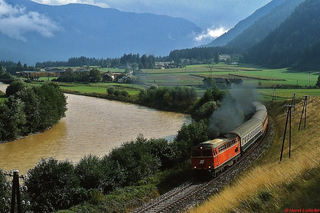 Nach einem heftigen Sommergewitter ist eine 2043 im September 1983 bei Sachsenburg im Drautal unterwegs. Der erste Wagen des Zuges ist ein DB-Kurswagen.