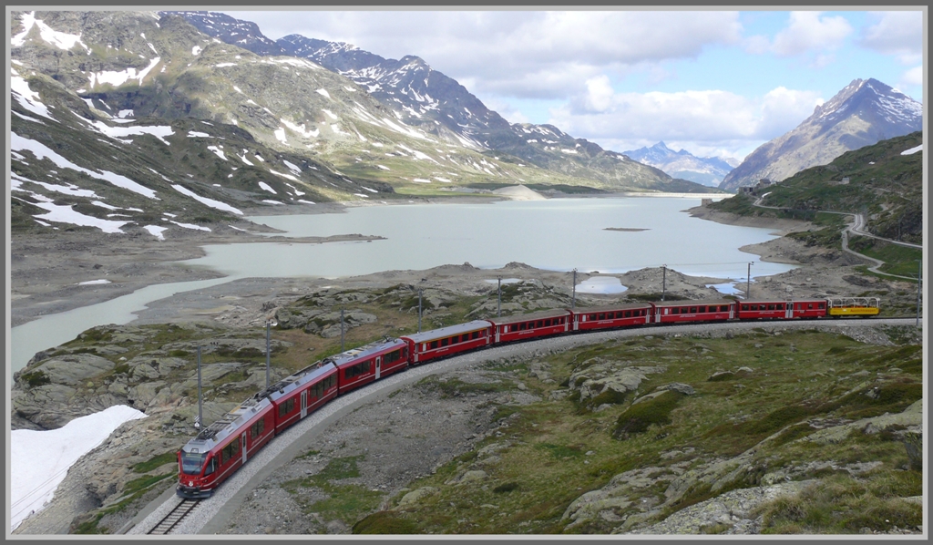 Nach einem strahlend schnen Morgen machen sich schon bald die ersten  Fotowolken  bemerkbar. R1621 mit ABe 8/12 windet sich dem halbvollen Lago Bianco entlang Richtung Sden. (15.06.2011)