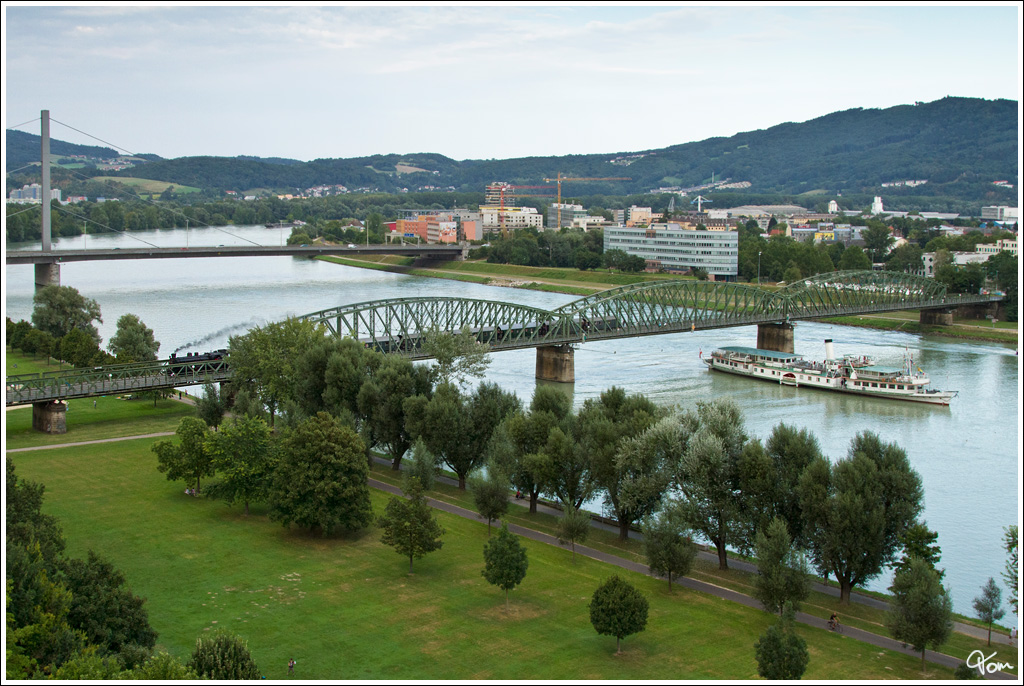 �GEG 77.28 �berquert mit dem IGE Sonderzug 17238 (Steyr - Linz Urfahr) die Donau. Im Vordergrund f�hrt der Schaufelraddampfer  Sch�nbrunn . Danke wieder einmal an die Organisatoren dieser wunderbaren Fahrt !!!  
Linz 24.8.2012  