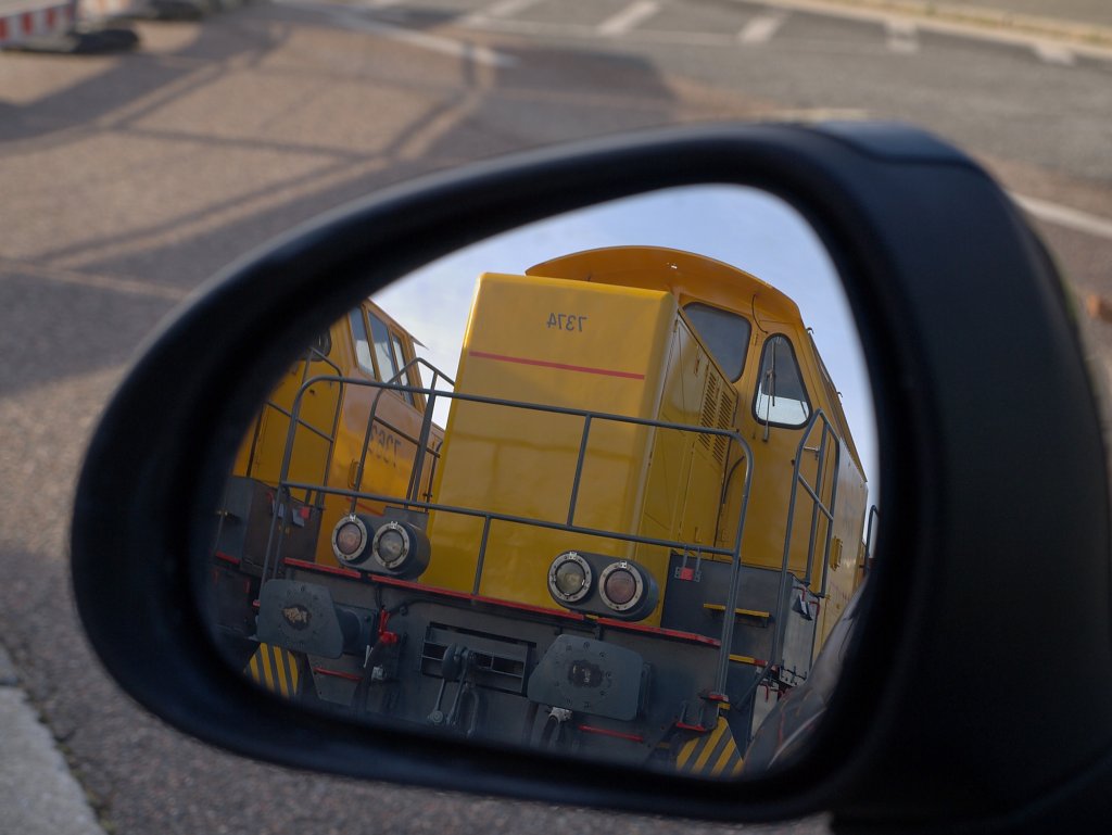 Oh weia, was habe ich den da im Rckspiegel? Die frisch restaurierten und in Gelb gespritzten belgischen Loks 7374 und 7363 stehen zur Zeit auf dem Autobahngrenzbergang Lichtenbusch an der A44 auf dem Parkplatz. Sie sollten aus Belgien nach Italien per Lkw auf Tiefladern transportiert werden. Bei einer Kontrolle am Zoll in Lichtenbusch bei der Einreise nach Deutschland fiel den Beamten auf, das die ca. 50to. schweren Lok´s auf Tiefladern standen die max. 28to. tragen drfen. Das war das vorlufige ende der Reise in den Sden. Nun stehen die zwei auf Balken statt auf Schienen auf dem Parkplatz der Zollanlage und warten auf ein Fahrzeug das diese Last tragen kann. Aufnahme vom 20.11.2010.