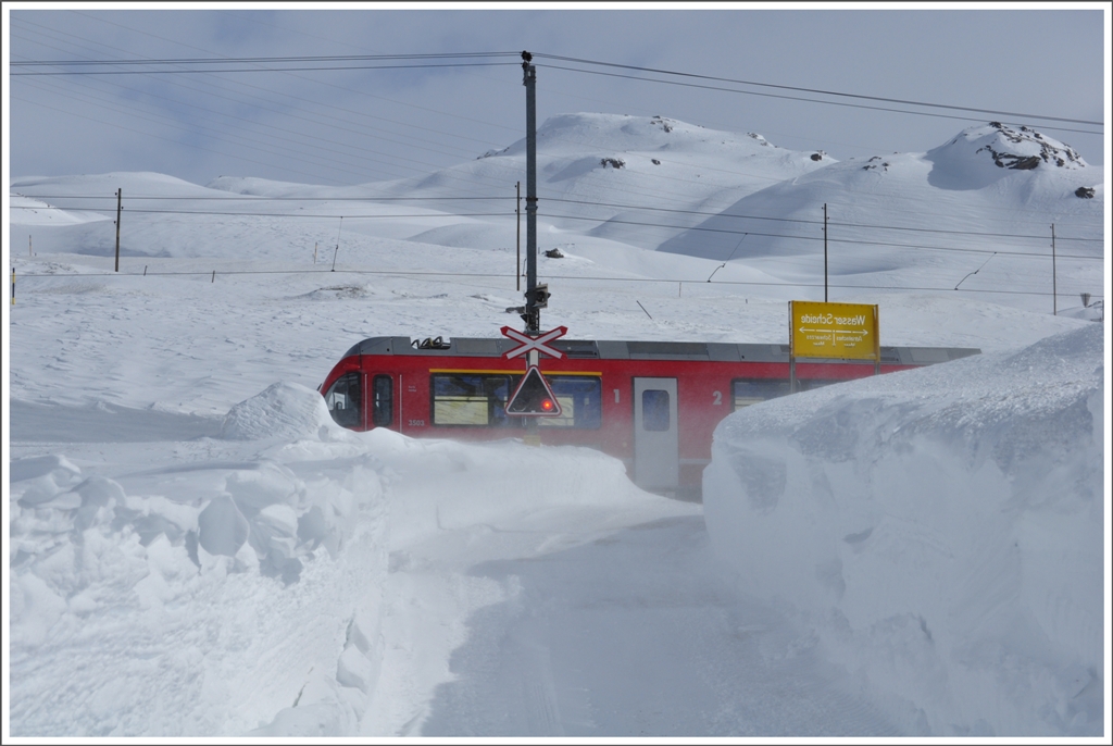 R1640 mit Allegra 3503  Carlo Janka  passiert die Wasserscheidetafel und den Bahnbergang zum Kieswerk auf der andern Seite des Lago Bianco. Diesen Winter wurde die Zufahrt zum Kieswerk offengehalten. (22.02.2011)