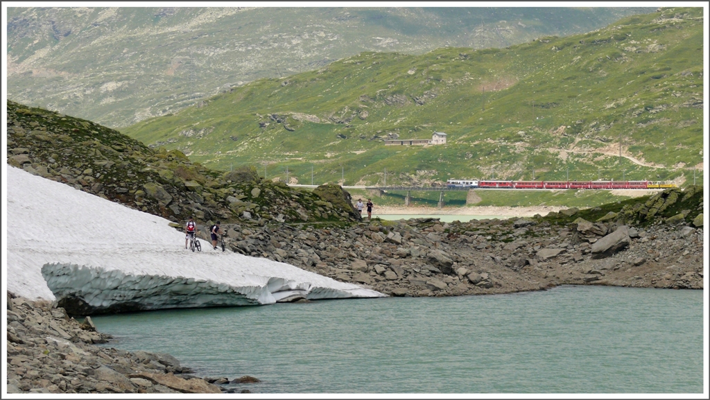 R1648 befhrt die Sonnenseite des Lago Bianco. Auf der Rckseite liegt noch Lawinenschnee, der bis in den See reicht. Hoffentlich hlt die Brcke.(14.07.2010)