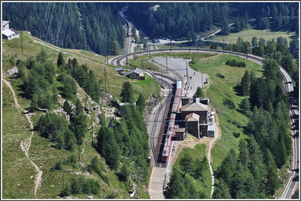 R1656 hlt in Alp Grm und gleich dahinter folgt BerninaExpress 950, der im Hintergrund sichtbar ist. Er ist noch 400m tiefer und 20 Minuten entfernt bei der Einfahrt der Station Cavaglia. Aufnahme von Sassal Masone. (11.08.2012)