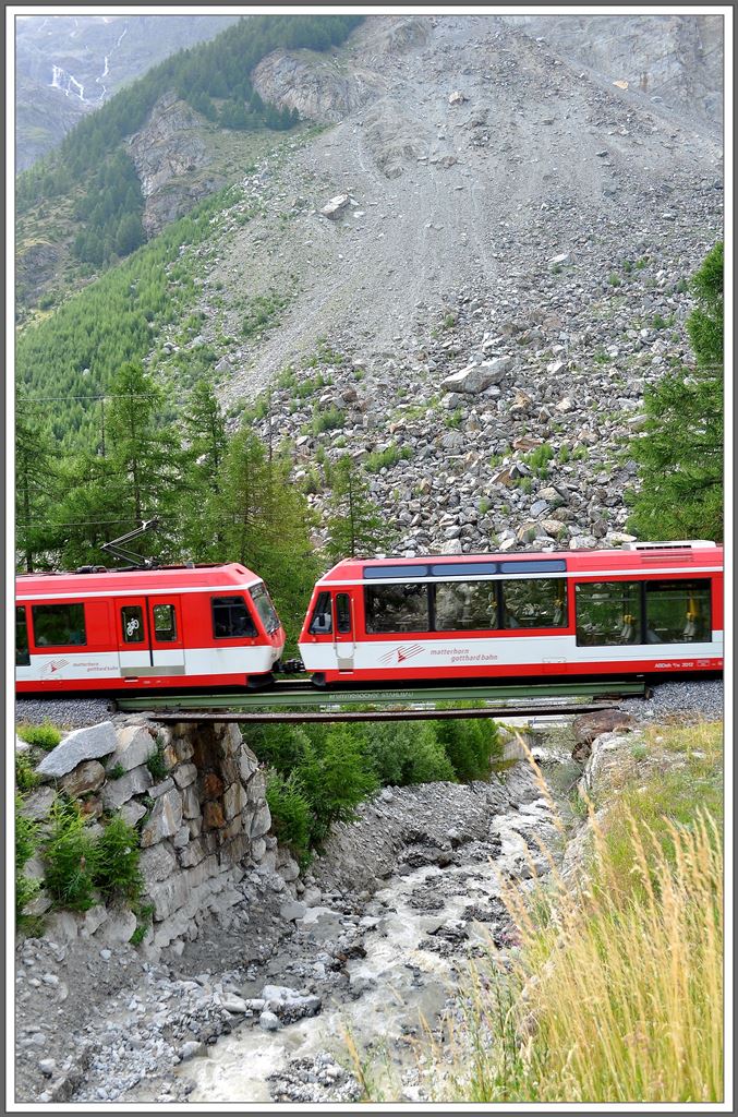 R258 mit einem ABDeh 4/10 und ABDeh 4/8 auf der Dorfbachbrcke in Randa mit dem Felssturzgebiet von 1991 im Hintergrund. (04.08.2013)