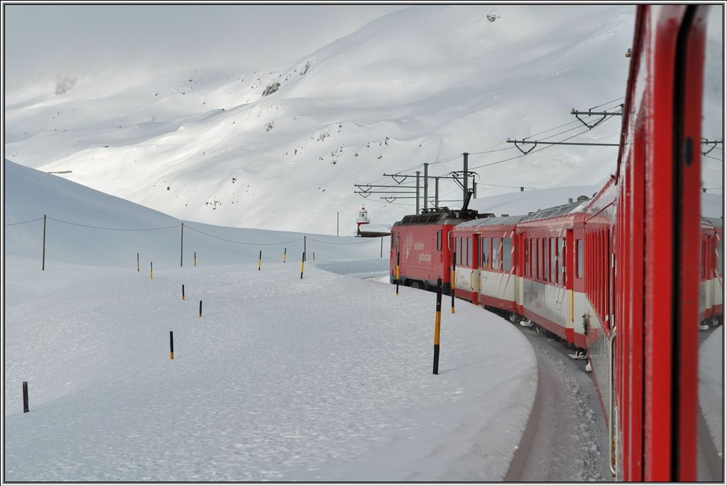 R827 kurz vor dem Oberalppass mit der eingeschneiten Strasse nebenan und dem Leuchtturm auf dem Pass. (19.12.2012)
