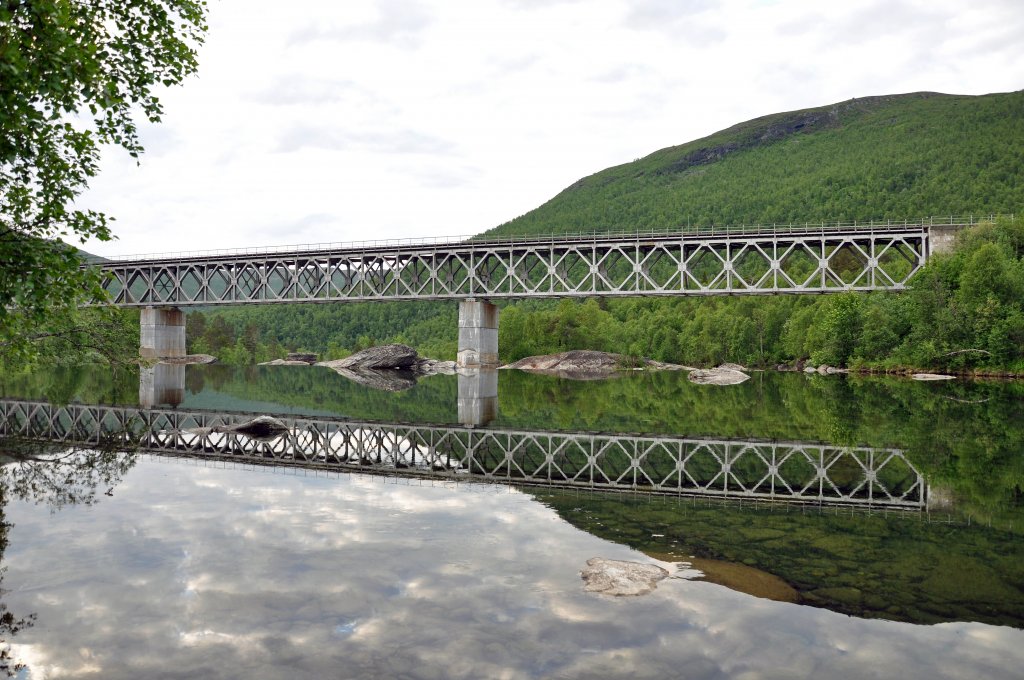 Raufjellfossen bru. Die Brcke und dieser Abschnitt der Nordlandsbahn (Nordlandsbana) entstand whrend der Zeit der deutschen Besatzung im Zweiten Weltkrieg. Fr den Bau wurden vorwiegend osteuropische Zwangsarbeiter herangezogen, von denen viele ihr Leben liesen. Daran sollte man bei aller Attraktivitt des Motivs und der Spiegelung, auch einmal erinnern. Aufnahme vom 03.07.2010, Tour nach Narvik. 