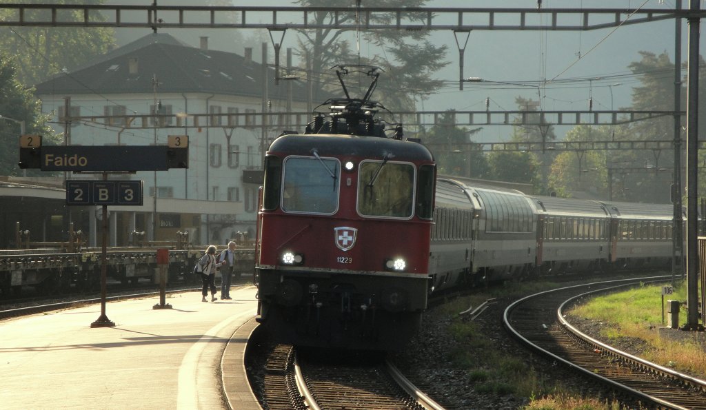 Re 4/4  11229 erreicht am 16.09.11 Faido. Das alte Paar drfte wohl nicht das Aussehen der Lok, sondern der Standort des Panorama-Wagens interessiert haben.
