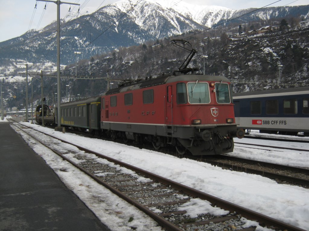 Re 4/4 II 11195 mit dem ATZ 27972 bei Einfahrt in Brig, Gleis 90. Am Schluss des Zuges ist ein BDt Auto (speziell umgebaut fr die Autozge) und die Swiss Express Re 4/4 II 11109 (geschleppt) angehngt, 19.01.2012.