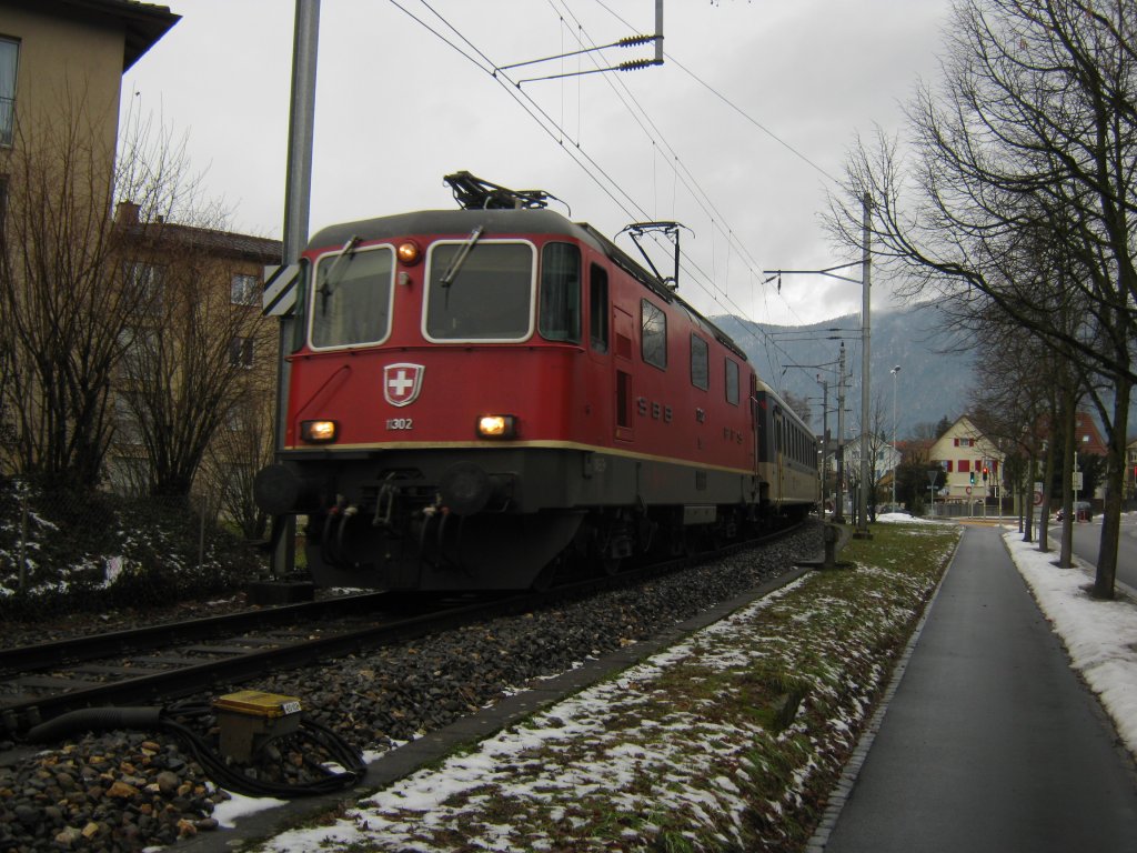 Re 4/4 II 11302 mit Regio 6847 (mit BDt am Schluss) bei Ausfahrt in Langendorf, 06.01.2011.