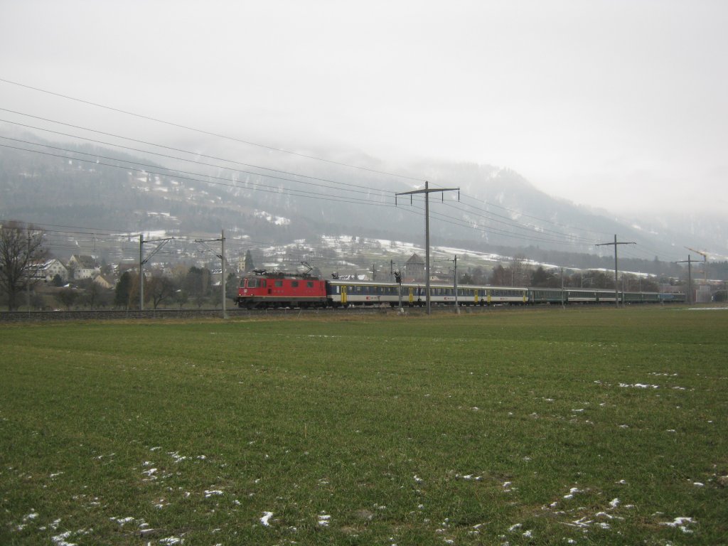 Re 4/4 II mit IC 10574 zwischen Maienfeld und Bad Ragaz. Dieser Entlastungszug wurde offensichtlich aus allem verfgbaren Rollmaterial zusammengestellt: 3 A EWI NPZ, 2 Bpm 51 und 5 B EWII, 02.01.2011.