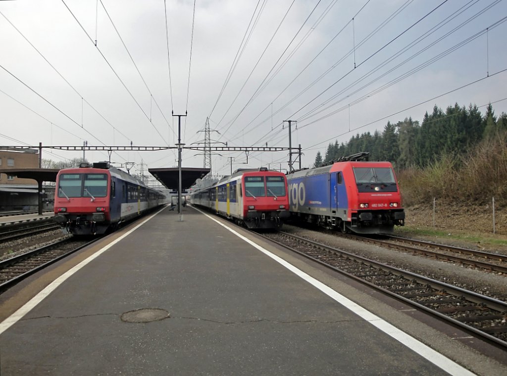 Rote Kpfe: Zwei NPZ stehen am 09.04.10 in Othmarsingen, whrend dem die Re 482 047-8 den Bahnhof durchfhrt. Der Perron befindet sich durch die vielen Gterzge pro Tag auch nicht in einem einwandfreien Zustand.