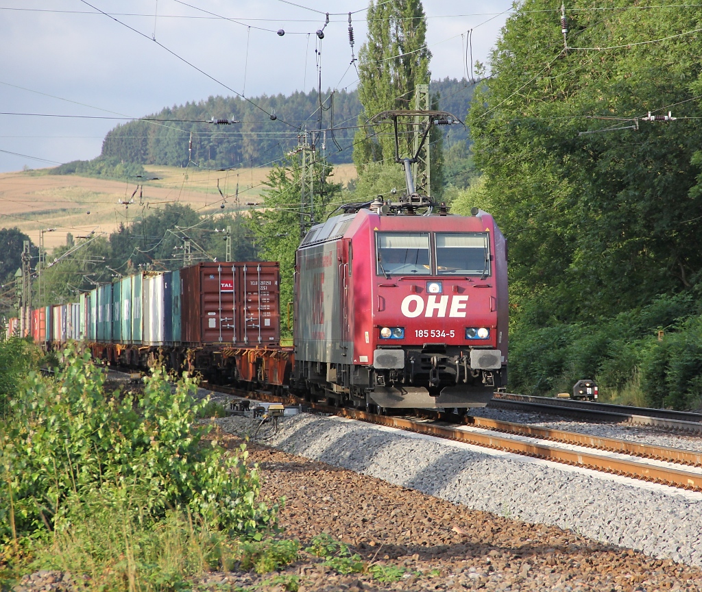 Roter Teint und blaue Augen: 185 534-5 der OHE mit Containerzug in Fahrtrichtung Norden. Aufgenommen am 22.07.2011 am B Eltmannshausen/Oberhone.