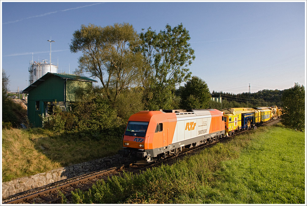 RTS 2016.906 zog am 23.9.2011 den SGAG48883 mit Gleisstopfmaschienen von Simbach Richtung Wels. Hier eine Aufnahme bei km 19.2. Im Hintergrund ist die Abfüllanlage der RAG zu sehen.