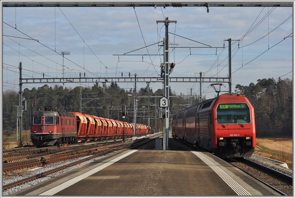 S5 nach Pfffikon SZ  mit Re 450 039-3 fhrt in Hntwangen-Wil ein. Die Re 6/6 11609  Uzwil  wartet mit einem beladenen Kieszug auf eine Lcke im dichten Fahrplan. (08.03.2013)