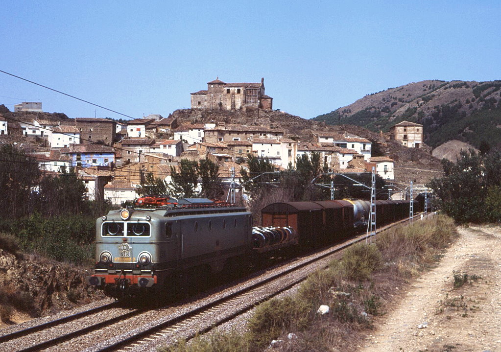 Samstag Mittag irgendwo mitten in Spanien - langes Warten bei ungemtlichen Temperaturen wurde dann belohnt: 276 083 (Bauart SNCF CC7100) fhrt vor der Kulisse des halb verfallenen Dorfes Bubierca auf der Strecke Madrid - Zaragoza, 08.09.1990.