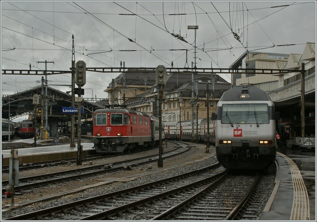 SBB RE 460 107-6 mit eine IC nach St. Gallen und die Re 4/4 II 11114 mit einem  IR nach Brig warten am feuchten 12. Juni 2012 in Lausanne auf ihre Abfahrt. 
 