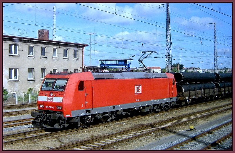 Schnellschuss aus dem Zugfenster.185 064-3 vor dem R�hrenzug -61343- unterwegs nach Mukran.  Stralsund am 01.07.08 