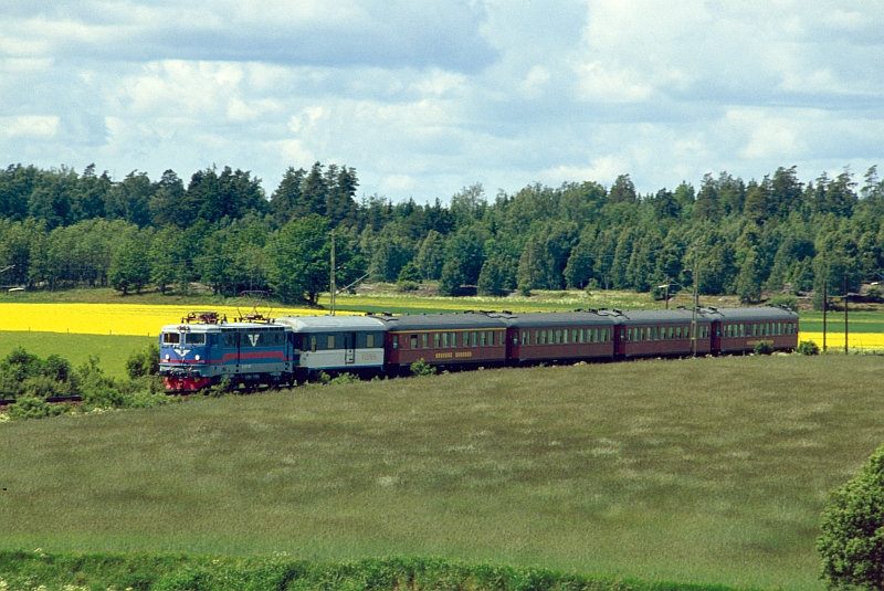 Schwedischer Sommer: Eine Rc3 der SJ durcheilt mit einem Intercity die wunderschne Sommerlandschaft im schwedischen Vrmland. Das Dia entstand im August 1994 zwischen Kristinehamn und Karlstad. 