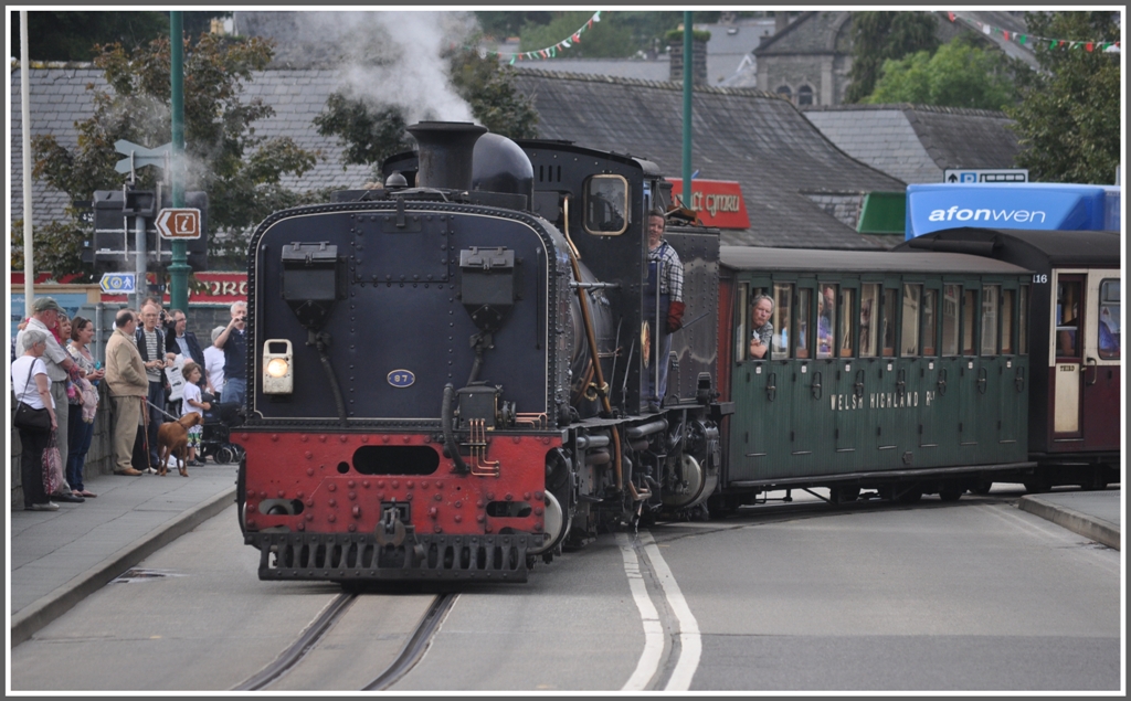 Seit April letzten Jahres hat auch die Welsh Highland Railway ihre Endstation in Porthmadog. Es brauchte anscheinend viel �berzeugungsarbeit bei der Stadt, um das kurze Verbindungsst�ck auf der Strasse erstellen zu d�rfen. Gesichert durch Ampeln und beobachtet von unz�hligen Touristen erreicht ein Dampfzug aus Caernarfon die Harbour Station in Porthmadog. (04.09.2012)