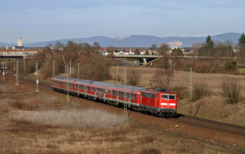 Seit Dezember 2009 setzt das Betriebswerk Ludwigshafen insgesamt f�nf Lokomotiven der Baureihe 111 ein. Die zuvor in M�nchen beheimateten Loks (111 030, 042, 045, 069 und 072) bespannen unter anderem auch flei�ig einige RB-Z�ge auf der KBS 700 zwischen Mannheim und Karlsruhe, die zuvor mit Triebwagen der Baureihe 425 gefahren wurden. Hier k�nnen die Loks zeigen, was in ihnen steckt, denn sie fahren im gleichen Fahrplan, wie die 425.
Am sonnigen 24. Februar 2010 verl�sst die Ludwigshafener 111 030 mit der RB 18619 von Mannheim nach Karlsruhe mit wenigen Minuten Versp�tung den Haltepunkt von Neulu�heim.