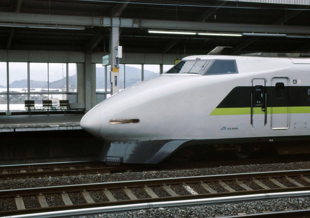 Serie 100: Das elegante Gesicht des Zuges mit Endwagen 122-5053 in Tokuyama. Durchs Bahnhofsfenster Blick auf die Schiffe im Hafen dieser Industriestadt. 6.Dezember 2005. 