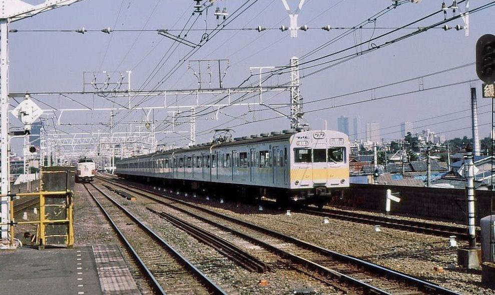 Serie 103-1200 (JR)/ Tokyo Metro Tôzai-Linie: Diese U-Bahn-tauglichen Züge (erkennbar an der Stirnwandtüre) mit gelben Streifen verkehrten über die Tôzai-U-Bahnlinie von Ost nach West unter Tokyo hindurch, gemeinsam mit den U-Bahn-eigenen Zügen. Heute sind sie durch neuere Fahrzeuge (Serie 231-800) ersetzt. Bild: Ueber den Dächern von Tokyo in Asagaya, Endwagen KUMOHA 102-1201. 6.September 1978. CHÛÔ-LINIE