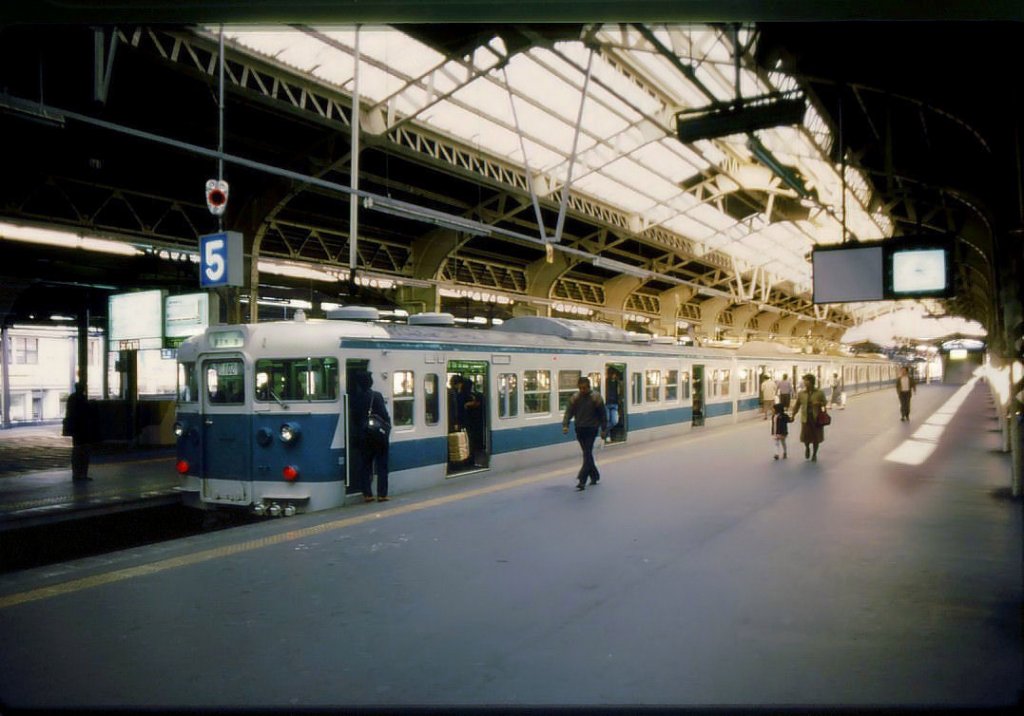 Serie 111 u.113 - Eilzüge im Kansai-Gebiet: Für Dienste von Osaka aus nach Süden nach Wakayama und auf die Kii Halbinsel mit ihren wilden Meeresküsten erhielten Züge einen Anstrich weiss mit blauem Streifen. Bild: Zug mit Endwagen KUHA 111-145 im Osaka-Tennôji, 25.März 1986. 