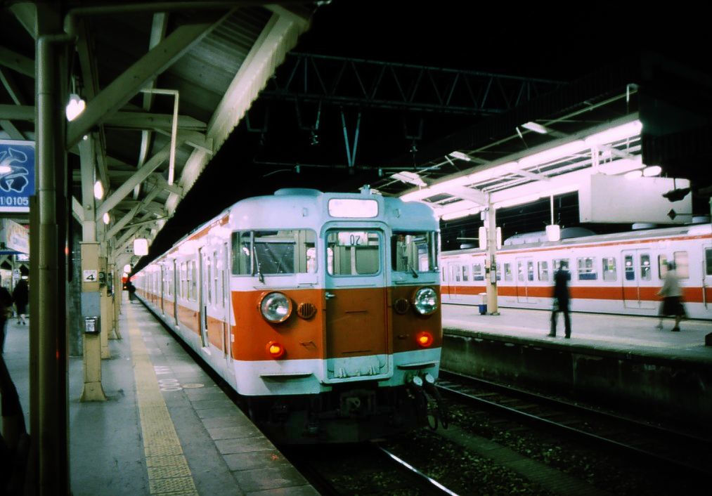 Serie 111 u.113 - Eilzüge im Kansai-Gebiet: Für Dienste östlich von Osaka und um die Stadt Nara herum erhielten mehrere Züge einen Anstrich weiss mit rotem Band, welches den dortigen feuerroten Schrein (Kasuga Taisha) symbolisiert. Bild: Zug mit Endwagen KUHA 111-93 in Nara, 26.März 1986. 