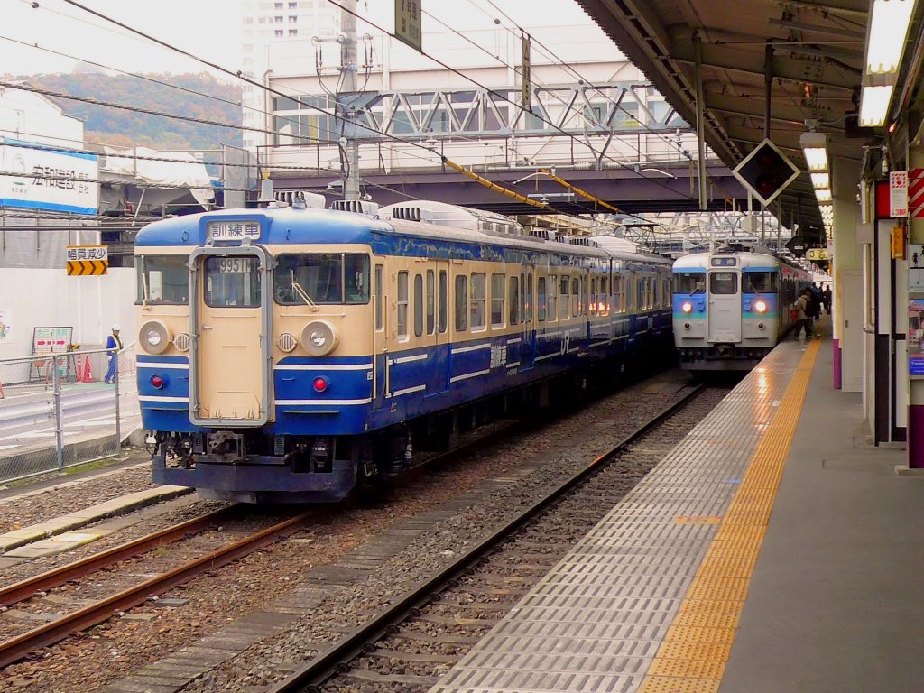 Serie 115 des zentraljapanischen Hochlands: Der Fahrschulzug (Endwagen KUHA 115-108) steht in Kôfu, während rechts der Linienzug (Endwagen KUHA 115-1058) zur Weiterfahrt auf das Hochplateau von Matsumoto bereitsteht. 24.November 2009. 
