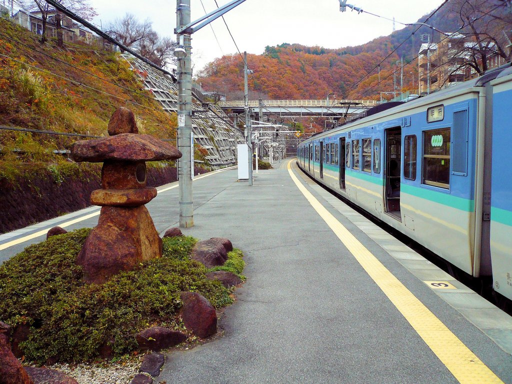 Serie 115 des zentraljapanischen Hochlands: Der Zug hat, von Tokyo herkommend, den Scheiteltunnel ins Bergtal von Yamanashi (alter Name: Kai) passiert und steht nun in Kai Yamato. Im Bild der Motorwagen MOHA 115-1038, 24.November 2009. 