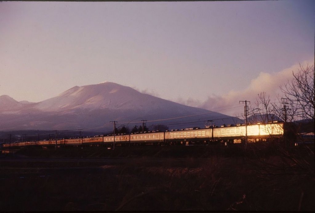 Serie 169: Bei Sonnenuntergang ein Zug vor dem Asama-Vulkan. Von rechts das Motorwagenpaar (Endwagen KUMOHA 169-3 und MOHA 168-3), dann die 2 Luxuswagen und der Speisewagen. Bei Naka Karuizawa, 13.Februar 1973. 