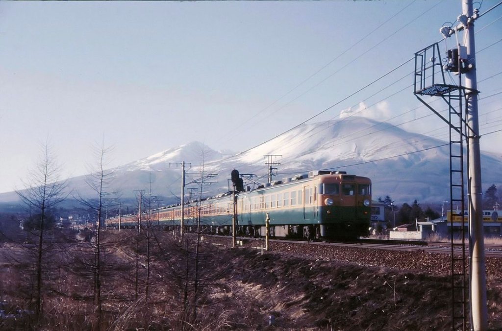 Serie 169: Wenige Tage nach einem schweren Ausbruch des Vulkans Asama eilt ein damaliger Schnellzug mit Endwagen KUMOHA 169-23 Richtung Naka Karuizawa; diese nach der Stilllegung der Usui-Rampe (und damit der durchgehenden Verbindung nach Osten/Tokyo) zur Stichbahn gewordene Strecke gehört heute der privaten Shinano Eisenbahn. 13.Februar 1973. 