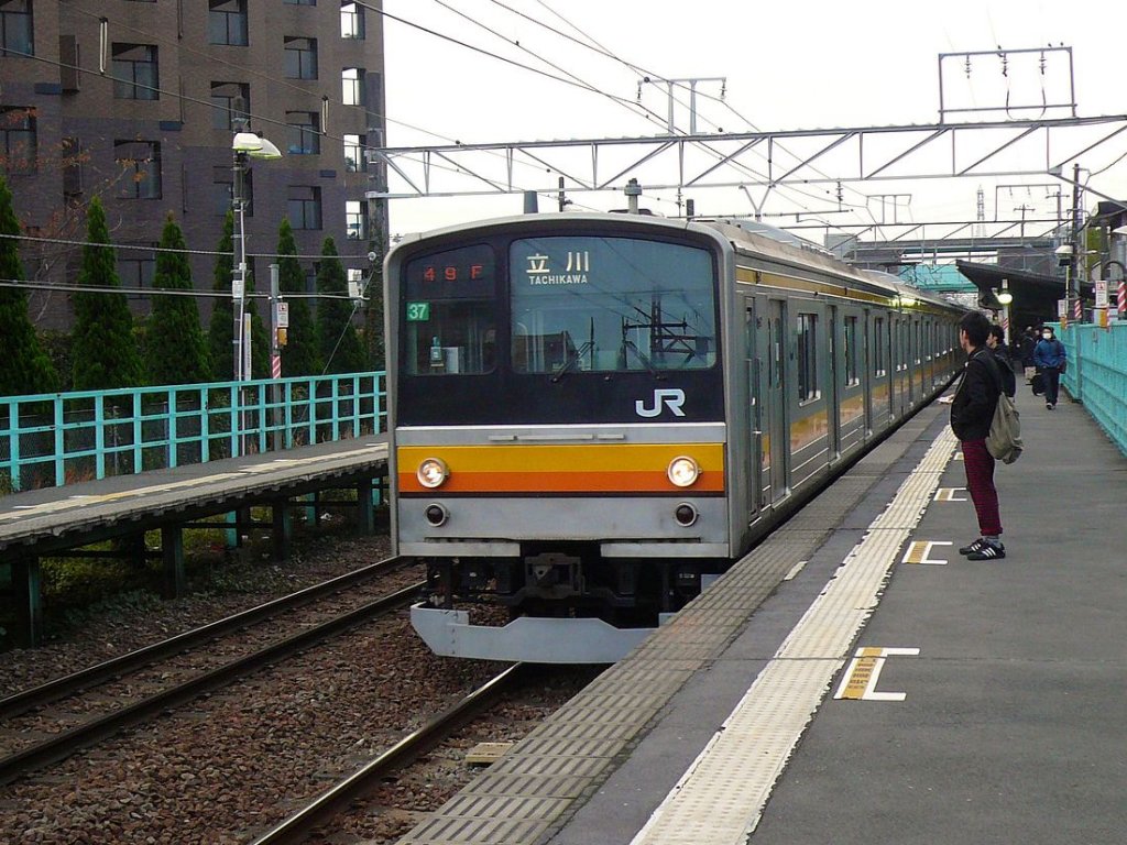 Serie 205: Nambu-Linie - Diese Linie am Westrand von Tokyo ist die stadtnähere der beiden Nord-Süd-Verbindungen durch eine noch bis in die 1970er-Jahre recht ländliche Gegend. Die Züge tragen ein orange-gelbes Band. Im Bild fährt ein 6-Wagenzug mit nordseitigem Steuerwagen KUHA 204-21 (heute in Indonesien im Einsatz) an der Spitze in Tokyo-Nishi Kunitachi ein, 23.November 2009. NAMBU-LINIE