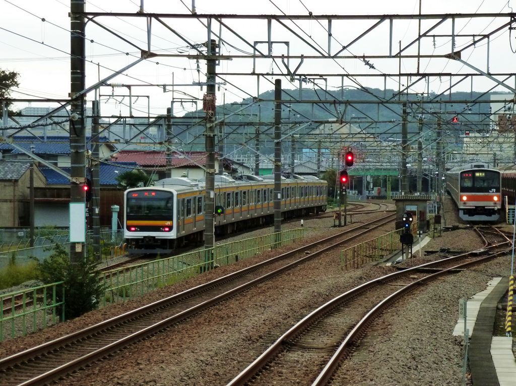 Serie 209: Der allerletzte Zug mit Originalwagen verkehrt heute auf der Nambu-Linie, einer Nord-Süd-Verbindung am westlichen Stadtrand von Tokyo. Farbband orange/gelb. Im Bild fährt dieser Zug (mit Endwagen KUHA 208-68) links aus der Station Fuchû Honmachi aus, während rechts ein Zug der Serie 205 auf seinen Einsatz auf der Musashino-Linie (die äussere Ringlinie um Tokyo herum) wartet. 24.Oktober 2011.  NAMBU-LINIE 