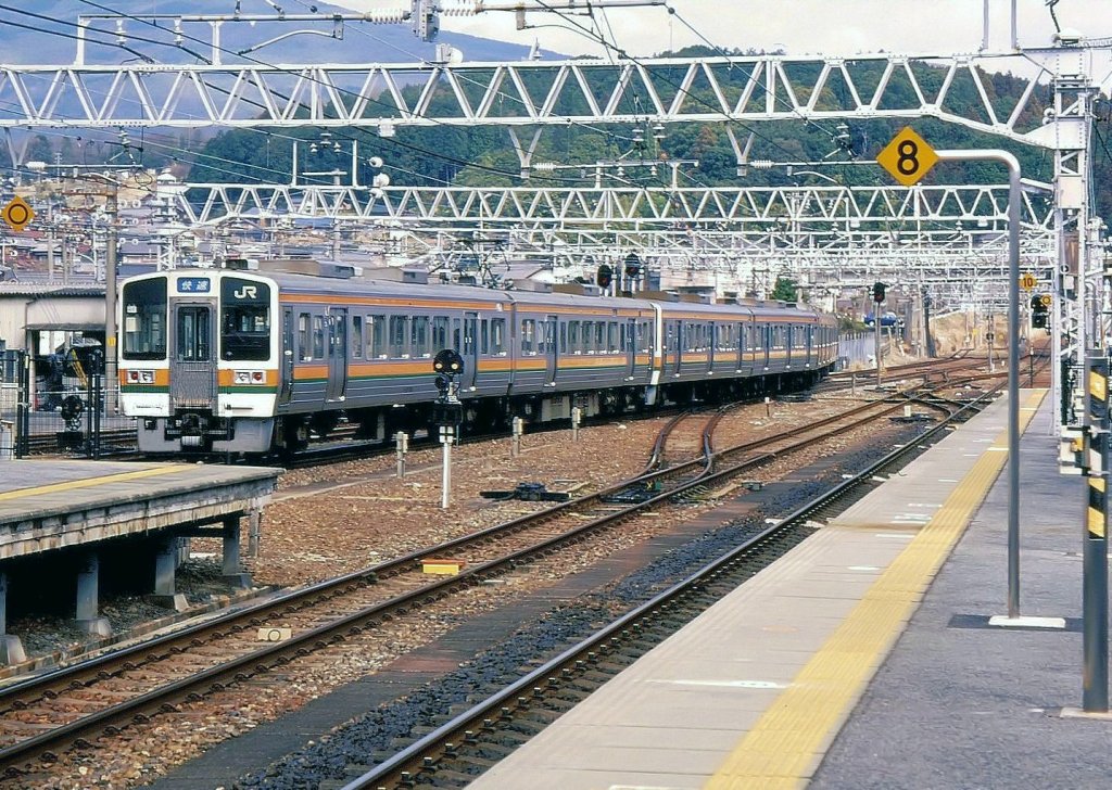 Serie 213: 1987-1991 gebauter Zug für Lokal- und Eilzugsverkehr. Für den Einsatz in Zentral- und Westjapan war ein besonders bequemer Innenraum erforderlich, da hier die Konkurrenz zu den grossen Privatbahnkonzernen enorm ist. Im Gegensatz zum damaligen neuen Lokal- und Eilzugstyp 211 hat die Serie 213 nur 2 Seitentüren, dafür gut gepolsterte Quersitze mit umlegbaren Rückenlehnen. 14 Zweiwagenzüge für JR Tôkai (JR Central, Raum Nagoya) gebaut, und 31 Wagen sowie 6 Panorama-Steuerwagen für JR West (Raum Okayama). Im Bild ist der Zweiwagenzug von JR Tôkai KUHA 212-5011 (Steuerwagen)+ KUMOHA 213-5011 (motorisierter Wagen mit Führerstand) als Zusatzmodul einem Zug Serie 211 (mit einfacher Bestuhlung und 3 Seitentüren) beigegeben. Nakatsugawa, 4.März 2007. 