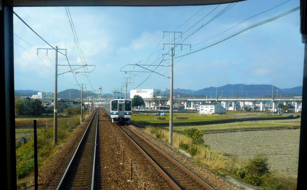 Serie 213: Einer der drei letzten Dreiwagenzüge dieser Serie von JR-West kommt in Tatsuno entgegen, geführt von KUMOHA 213-5. Im Hintergrund ist die Sanyô-Shinkansenlinie nach Westjapan und Kyûshû erkennbar. 26.September 2010. (Aufnahme durch die verglaste Führerstandrückwand eines Gegenzugs)