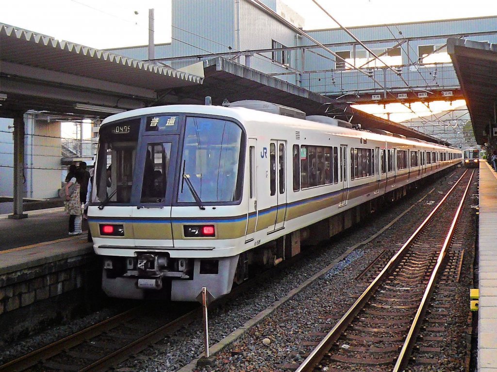 Serie 221: Eine grosse Serie von modernen Gleichstrom-Wagen der damals gerade neu gegründeten JR-West-Japan für Eilzüge zwischen den grossen Städten der Kansai-Region (Kyôto-Ôsaka-Kôbe), erbaut 1989/90. Zu 2-,4-,6- und 8-Wagenzügen formiert, total 474 Wagen. Typische Wagenanordnung in einem 6-Wagenzug: Steuerwagenクハ(KUHA) 221 – Zwischenwagenサハ(SAHA) 220 – motorisierter Wagenモハ(MOHA) 220 – Zwischenwagenサハ(SAHA) 221 – motorisierter Wagenモハ(MOHA) 221 – motorisierter Wagen mit Führerstandクモハ(KUMOHA) 221. Sehr bequeme Quersitze, in Fahrtrichtung umlegbar. Heute teilweise durch modernere Wagen in lokale Dienste um Kyôto, Ôsaka, Kôbe und Nara verdrängt. Im Bild ein 6+4-Wagenzug, Endwagen KUMOHA 221-60, in Kyôto-Yamashina, 24.September 2009.   
