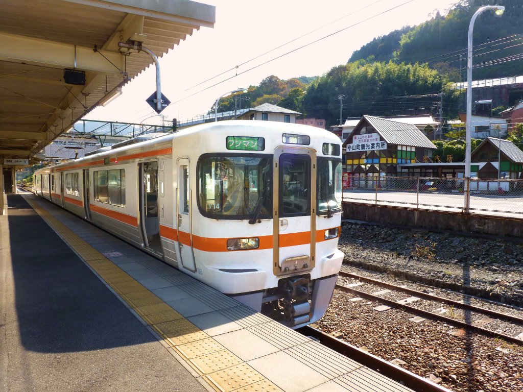 Serie 313-3000: Diese Züge haben bequeme Vis-à-vis-Sitzplätze und eignen sich gut für touristische Linien wie hier die Gotemba-Linie, die östlichste Linie von JR Tôkai. Diese Linie führt ganz nah an den Fuss des Fuji-Berges heran. Im Bild Steuerwagen KUHA 312-3102; im Hintergrund das bunte Haus ist die lokale Tourismuszentrale. Suruga Oyama, 2.November 2011. 